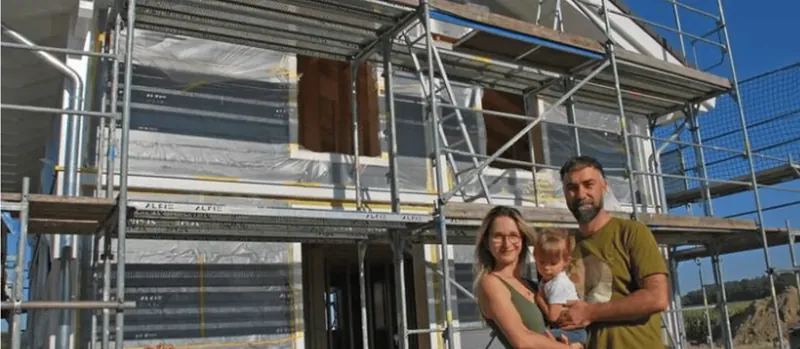 Bauherrenfamilie vor dem Rohbau ihres Eigenheims